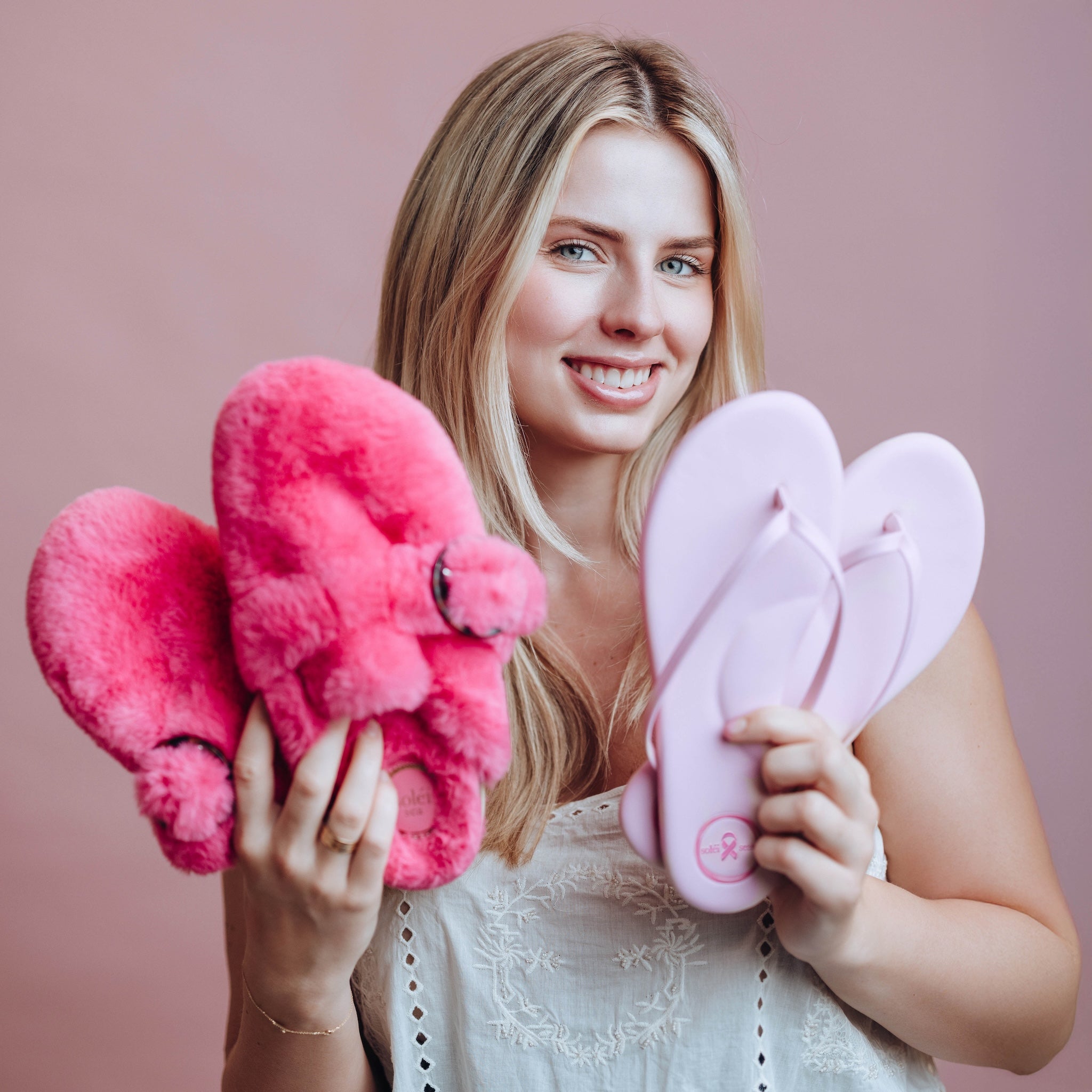 Model holding Solei Sea Fur Clog and Flip Flop in Pink Hope colorway to support Breast Cancer treatment.
